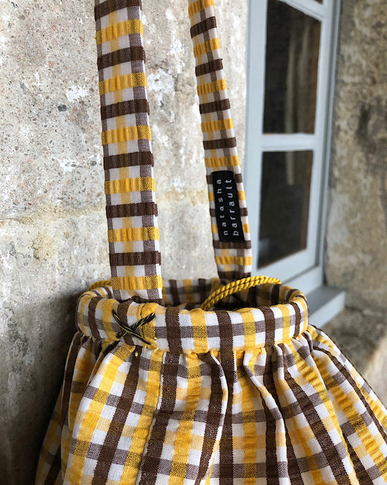 hand sewn detail at handle of vintage brown, yellow and white seersucker cotton basket with a adjustable handle, can be worn as a shoulder or handbag